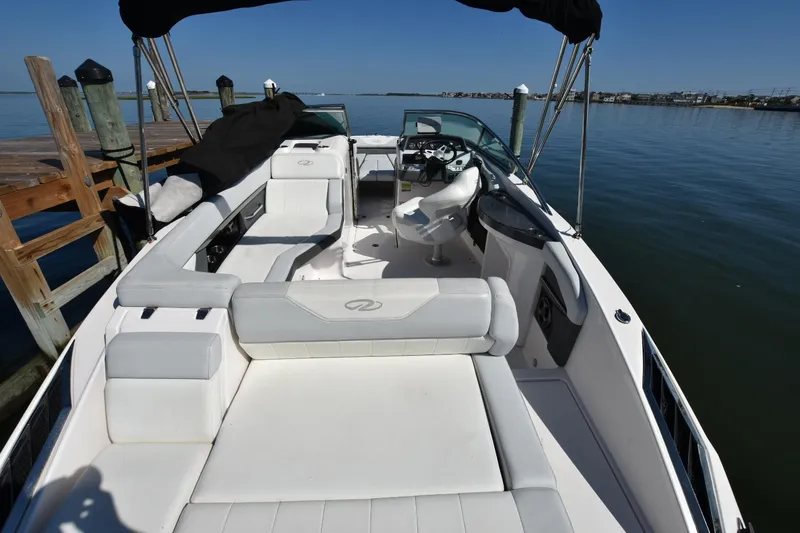 Slide: The Image of 2012 Regal 24 FasDeck boat interior with white seating, docked by calm waters. - 6