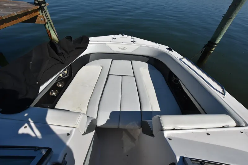 Slide: The Image of 2012 Regal 24 FasDeck boat interior with white seating, docked by calm water. - 8