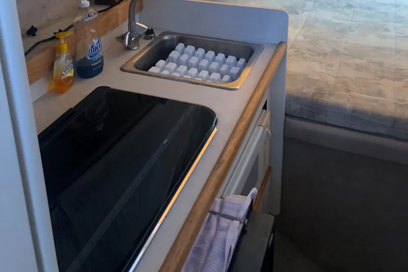 Slide: The Image of Compact kitchen area in a 1998 Bayliner 2452 Ciera Express boat with sink and stove. - 18