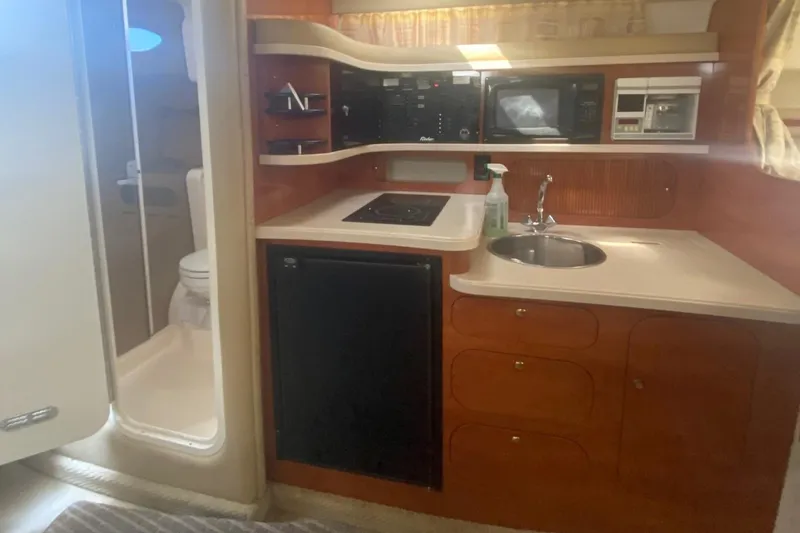 Slide: The Image of 2003 Rinker 342 Fiesta Vee boat interior kitchen with sink, stove, microwave, and refrigerator. - 11