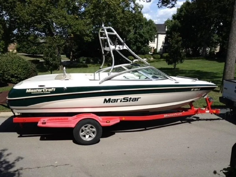 The Image of 1999 MasterCraft MariStar 210 boat on red trailer outdoors. - 1