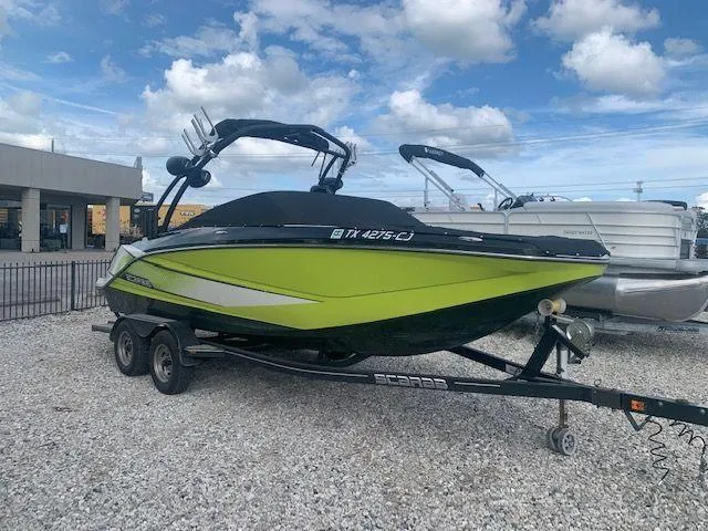 The Image of 2014 Scarab 215 boat on trailer, lime green and black, parked outdoors. - 0