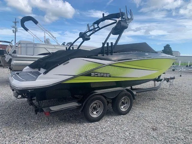 Slide: The Image of 2014 Scarab 215 boat on a trailer, green and white, parked on gravel. - 1