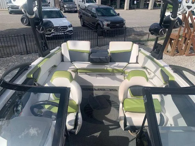 Slide: The Image of 2014 Scarab 215 boat interior with green and white seating, parked in a lot. - 12