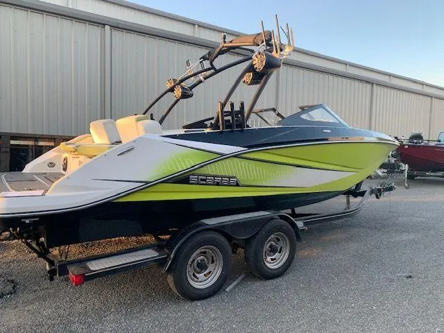 Slide: The Image of 2014 Scarab 215 boat on trailer, lime green and white, parked outdoors. - 18