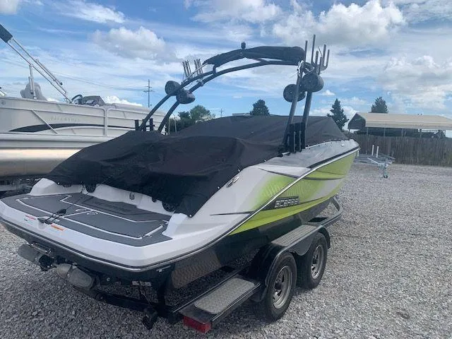 Slide: The Image of 2014 Scarab 215 boat on a trailer with a black cover, parked outdoors. - 3