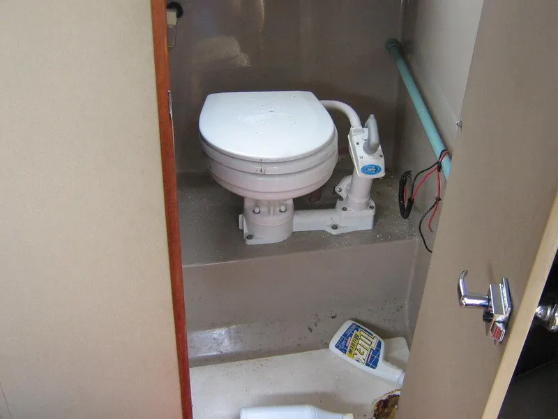Slide: The Image of 1983 Bayliner 2850 Contessa boat bathroom with marine toilet and cleaning supplies. - 11