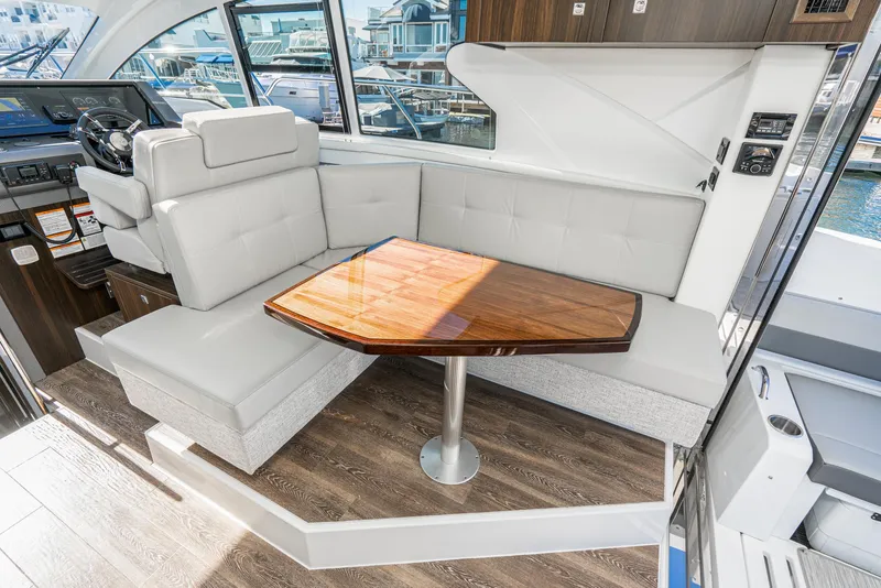 Slide: The Image of Interior seating area of 2023 Cruisers Yachts 42 Cantius with wooden table and white upholstery. - 24