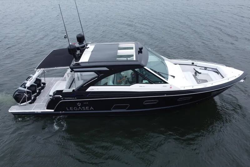 Slide: The Image of 2022 Formula 380 Super Sport Crossover OB boat on water, sleek design, black and white exterior. - 18