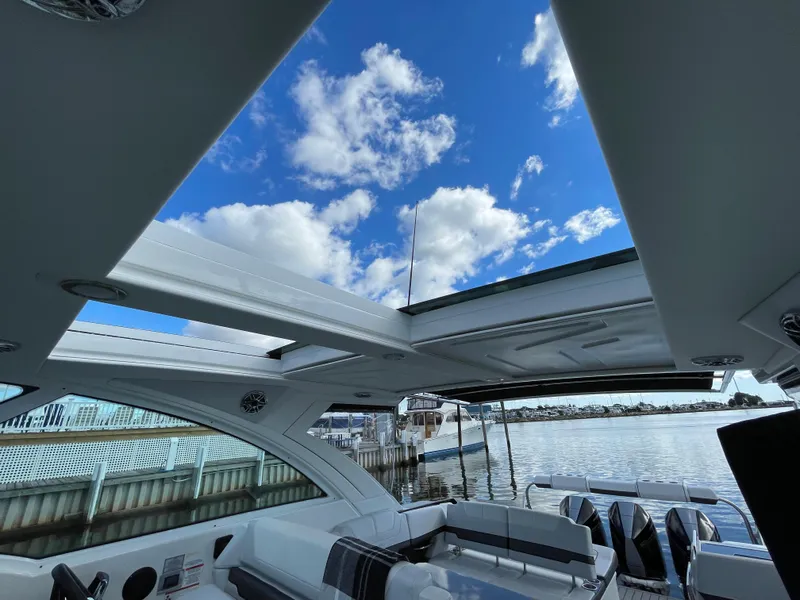 Slide: The Image of 2022 Formula 380 Super Sport Crossover boat interior with open sunroof and waterfront view. - 36