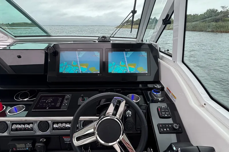 Slide: The Image of 2022 Formula 380 Super Sport Crossover OB helm with dual navigation screens on a calm waterway. - 73
