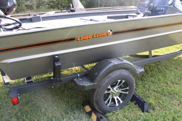 Slide: The Image of 2023 Lowe Legacy boat on trailer, side view, parked on grass. - 3