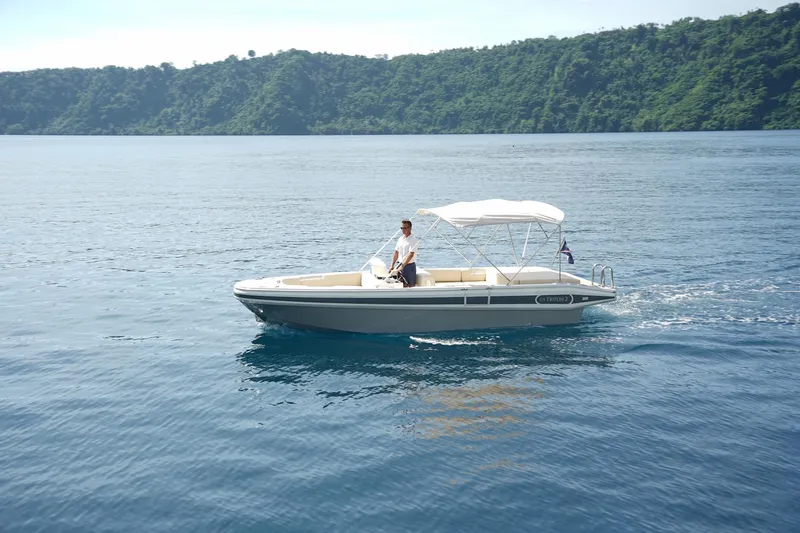 Slide: The Image of 2020 Novurania Chase boat cruising on calm waters with lush green hills in the background. - 4