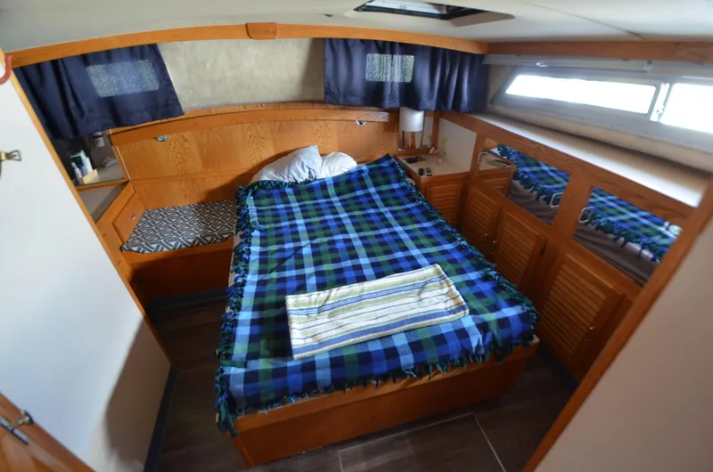 Slide: The Image of 1986 Silverton 40 Aft Cabin bedroom with plaid bedding and wooden cabinetry. - 22
