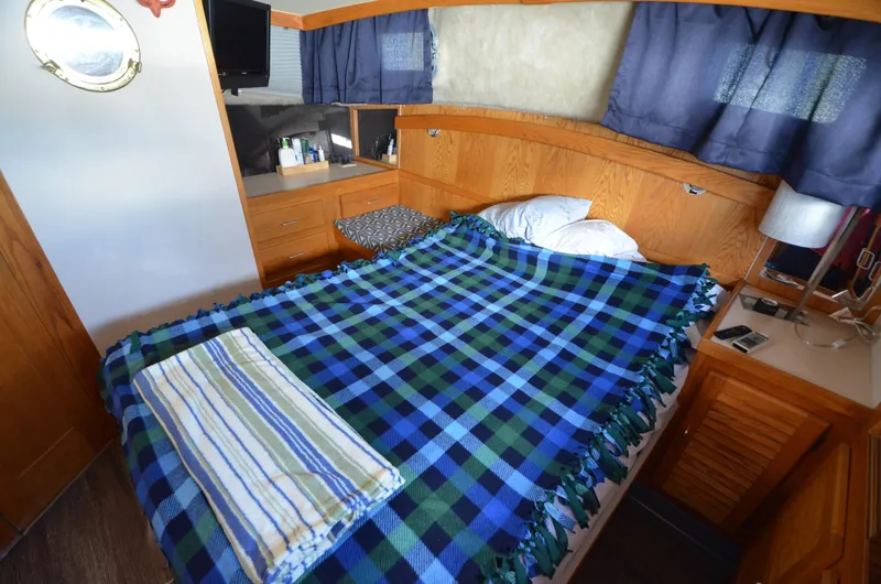 Slide: The Image of 1986 Silverton 40 Aft Cabin bedroom with blue plaid blanket and wooden cabinetry. - 23