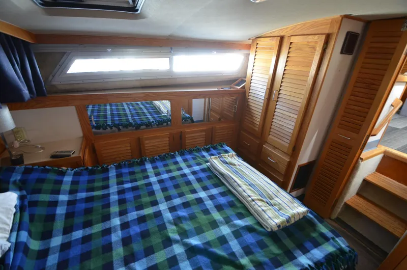 Slide: The Image of 1986 Silverton 40 Aft Cabin bedroom with plaid bedding and wooden cabinetry. - 25