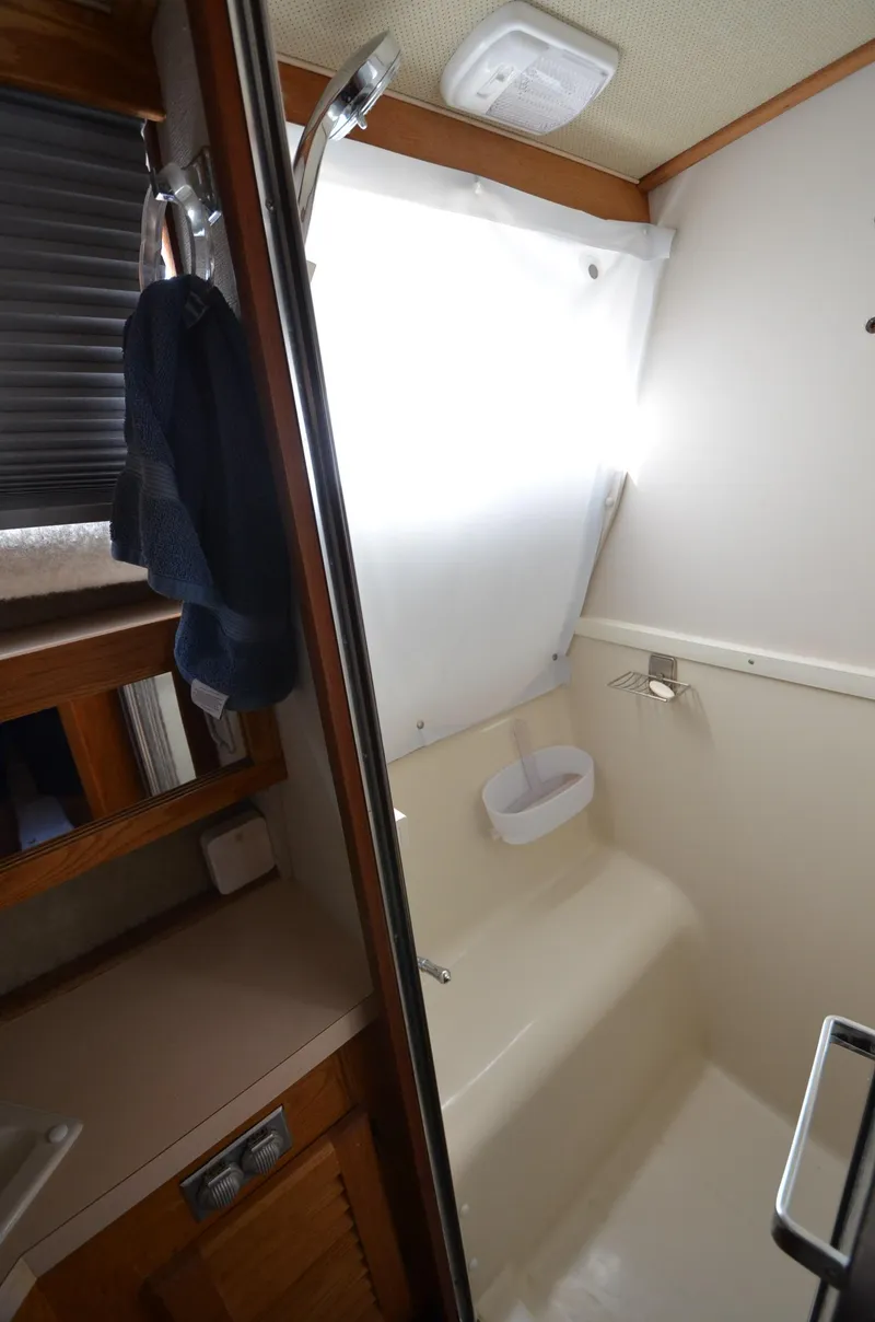 Slide: The Image of 1986 Silverton 40 Aft Cabin bathroom with shower and storage shelves. - 26