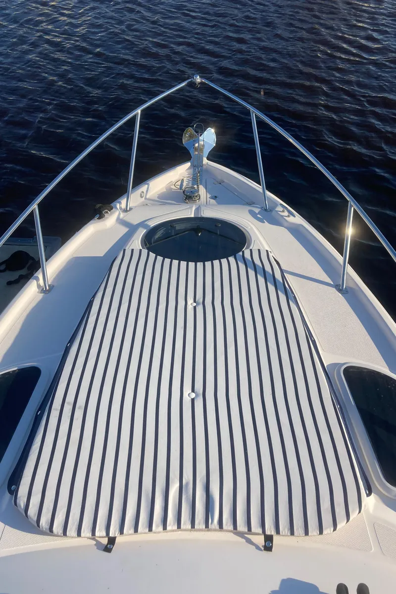 Slide: The Image of 2015 Regal 28 Express boat bow with striped sunpad and water background. - 13