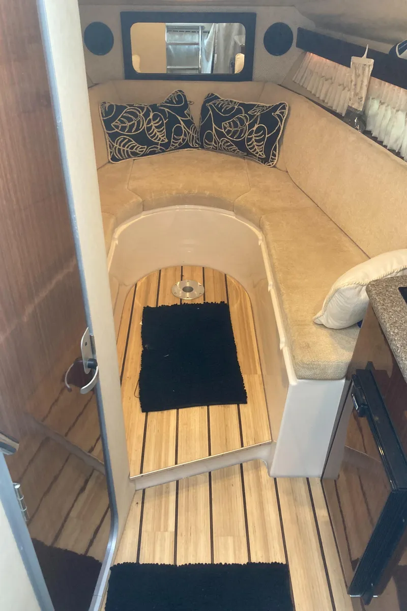 Slide: The Image of 2015 Regal 28 Express cabin interior with cushioned seating and wooden flooring. - 16