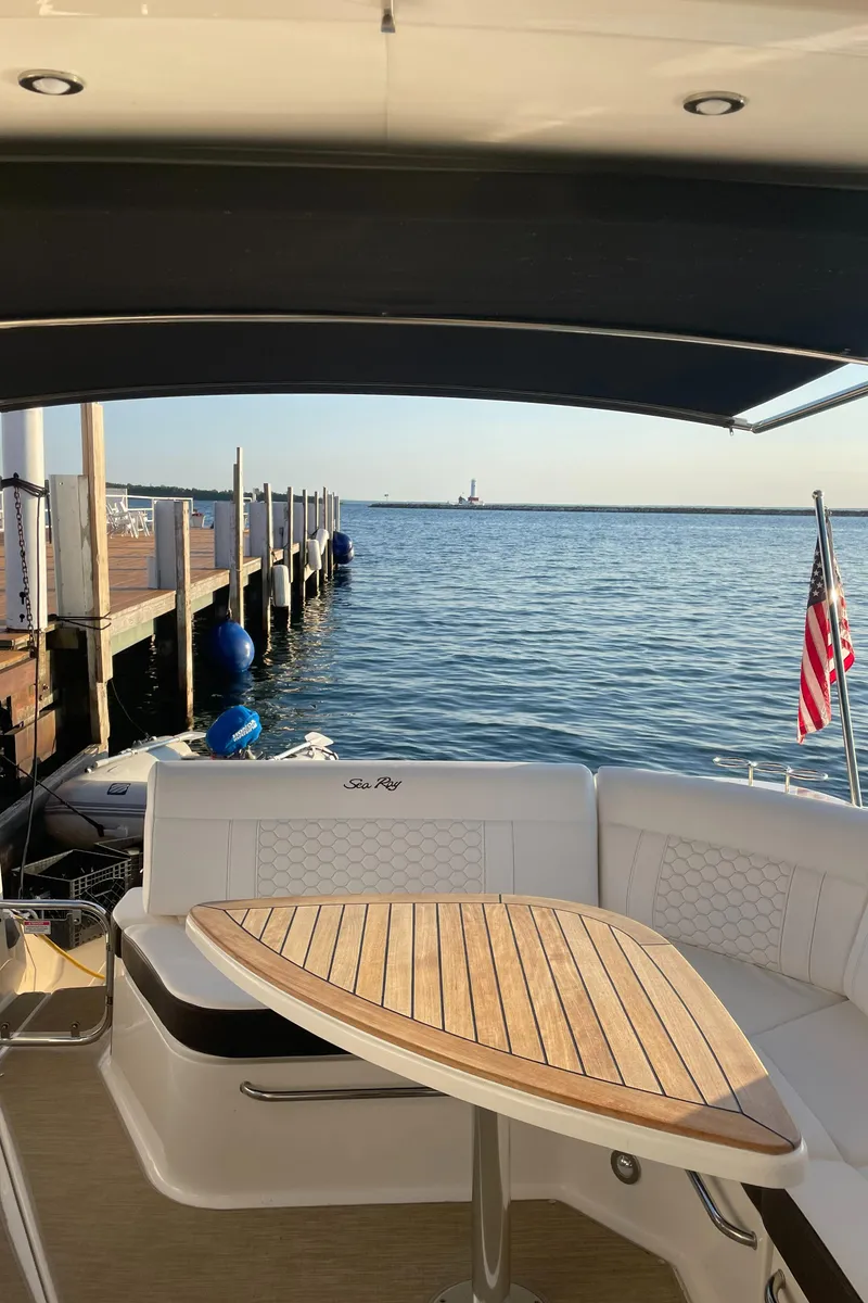 Slide: The Image of The image shows the stern of a 2020 Sea Ray Sundancer 320 with a wooden table and water view. - 18