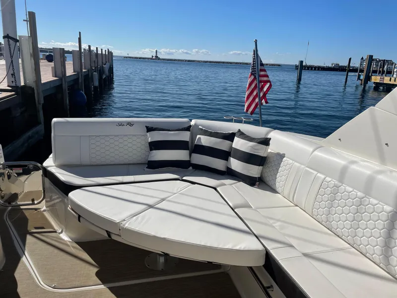 Slide: The Image of The 2020 Sea Ray Sundancer 320 features an elegant seating area with striped cushions by the water. - 21