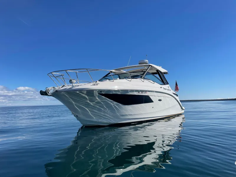Slide: The Image of The 2020 Sea Ray Sundancer 320 glides on calm water under a clear blue sky. - 3