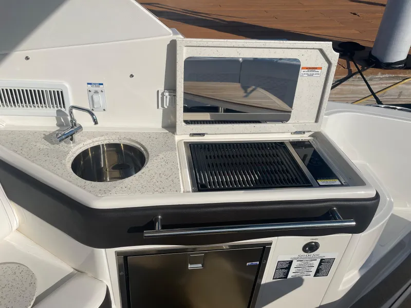 Slide: The Image of The 2020 Sea Ray Sundancer 320 features an outdoor kitchenette with a sink, grill, and refrigerator. - 24