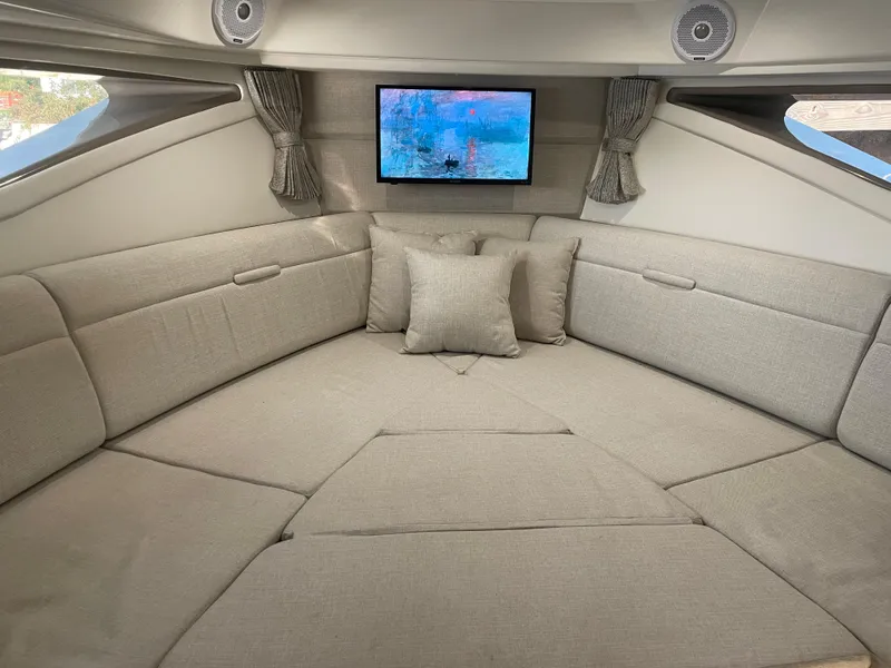 Slide: The Image of The 2020 Sea Ray Sundancer 320 cabin features a cozy seating area with a television. - 28
