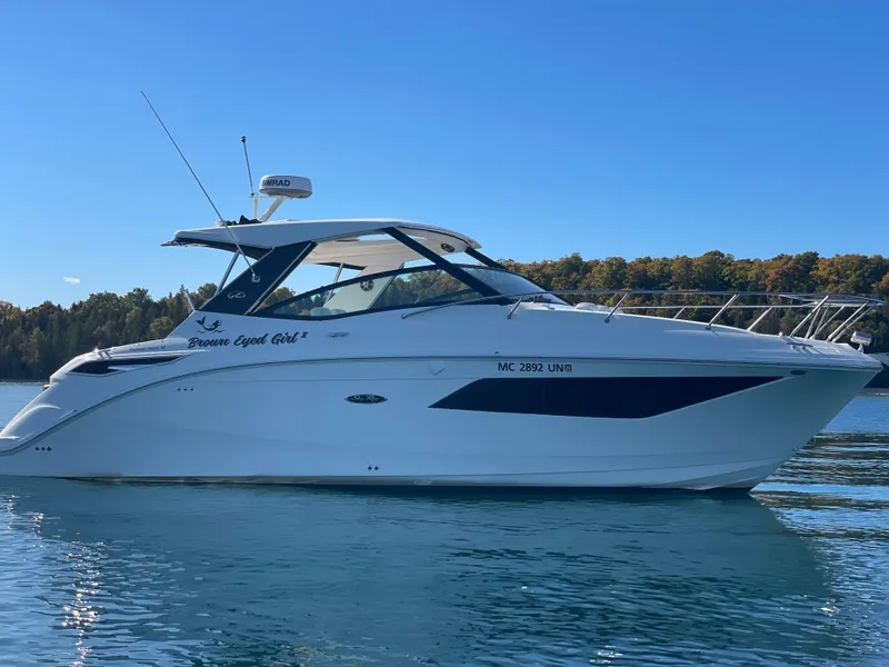 The Image of A 2020 Sea Ray Sundancer 320 on calm water, surrounded by trees in the background. - 0
