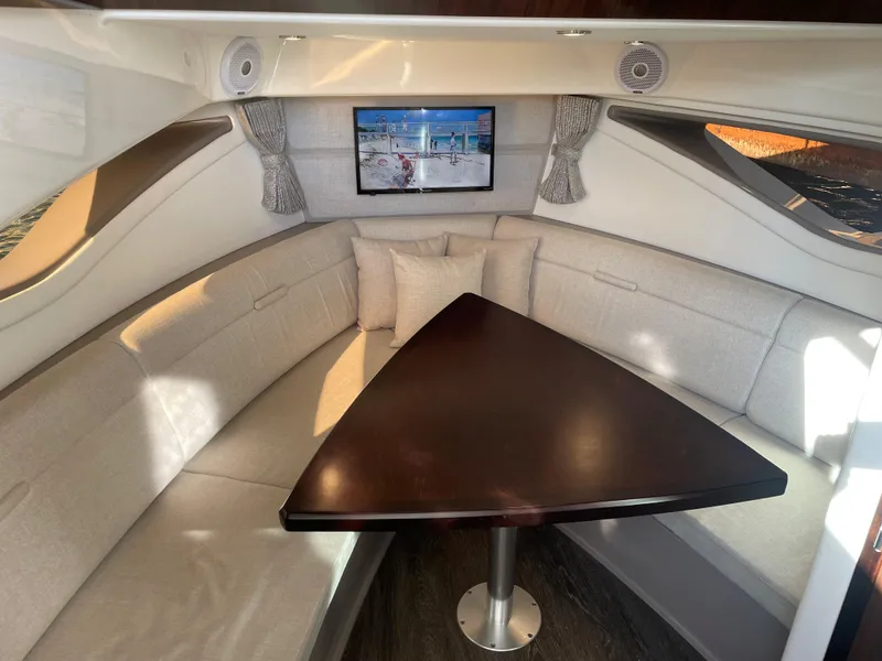 Slide: The Image of Interior of a 2020 Sea Ray Sundancer 320 featuring a sleek triangular wooden table and comfortable seating. - 27
