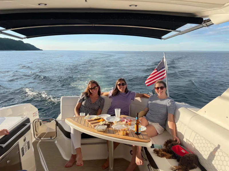 Slide: The Image of Three people sit on a boat with a table full of snacks. An American flag waves in the background. - 19