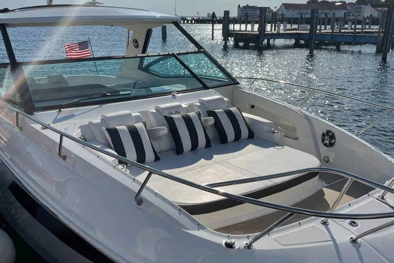 Slide: The Image of The 2020 Sea Ray Sundancer 320 is on the water, featuring a spacious sun deck with striped cushions. - 7