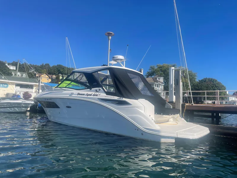 Slide: The Image of A 2020 Sea Ray Sundancer 320 docked at a pier. The sky is clear and blue. - 5