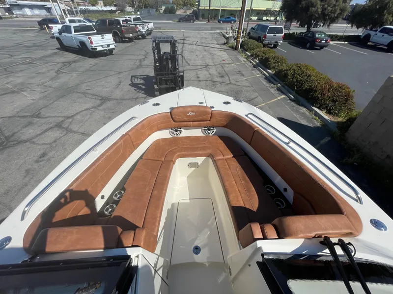 Slide: The Image of 2024 Scout 277 Dorado boat with spacious brown leather seating in a parking lot. - 11