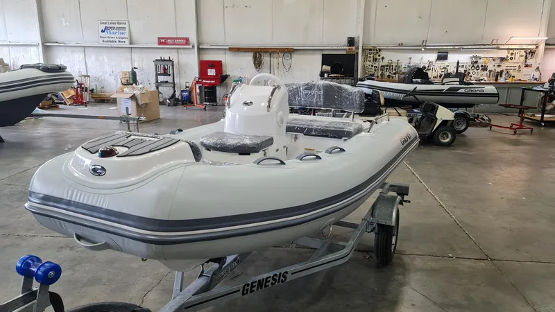 The Image of 2023 Grand Inflatables G380HLF boat in a workshop on a Genesis trailer. - 0
