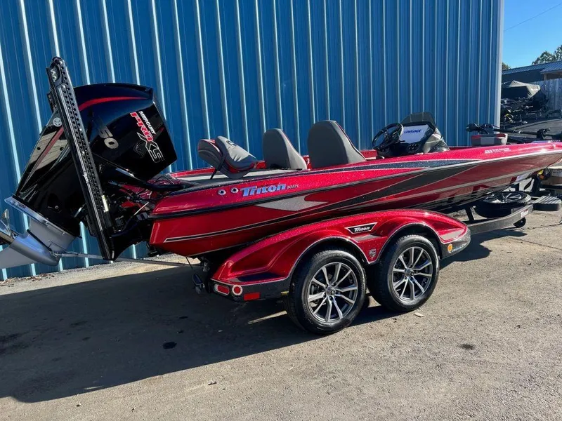 Slide: The Image of 2023 Triton 21 TrX Patriot bass boat in red, parked on a trailer. - 3