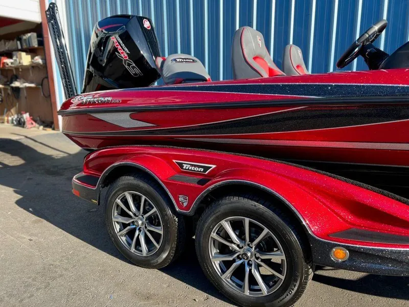 Slide: The Image of 2023 Triton 21 TrX Patriot boat, red and black, on a dual-axle trailer. - 5