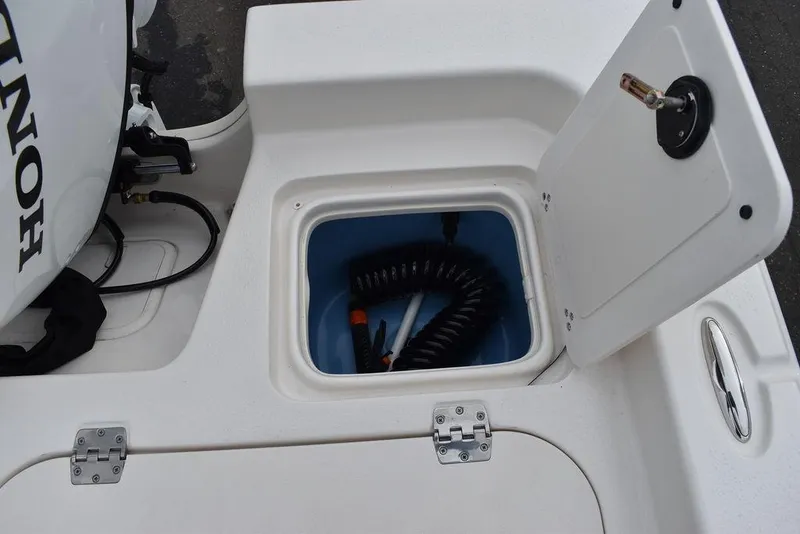 Slide: The Image of 2022 Carolina Skiff 19 Ultra Elite storage compartment with coiled hose and Honda engine. - 18