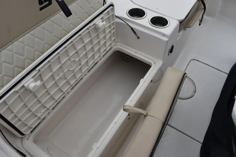 Slide: The Image of 2022 Carolina Skiff 19 Ultra Elite boat interior with storage compartment and cup holders. - 19