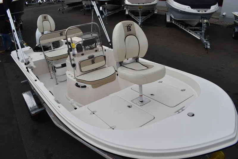 Slide: The Image of 2023 Carolina Skiff 178 JLS boat with white and beige seating, docked on a trailer. - 15
