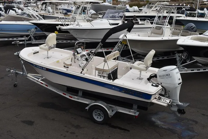 Slide: The Image of 2023 Carolina Skiff 178 JLS boat on trailer, surrounded by other boats in a marina. - 3