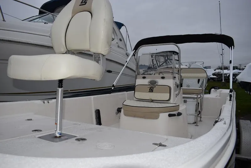 Slide: The Image of 2023 Carolina Skiff 192 JLS boat with seating and console, docked beside other boats. - 10