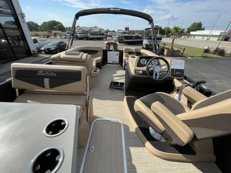 Slide: The Image of 2023 Barletta Cabrio 24 UE pontoon boat interior with tan and black seating, steering console, and cup holders. - 33