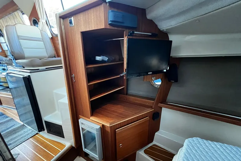 Slide: The Image of 2021 Ranger Tugs R-29S interior with wooden cabinetry, TV, and seating area. - 10
