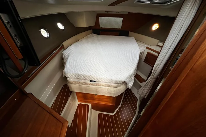 Slide: The Image of 2021 Ranger Tugs R-29S cabin interior with cozy bed and wooden flooring. - 11