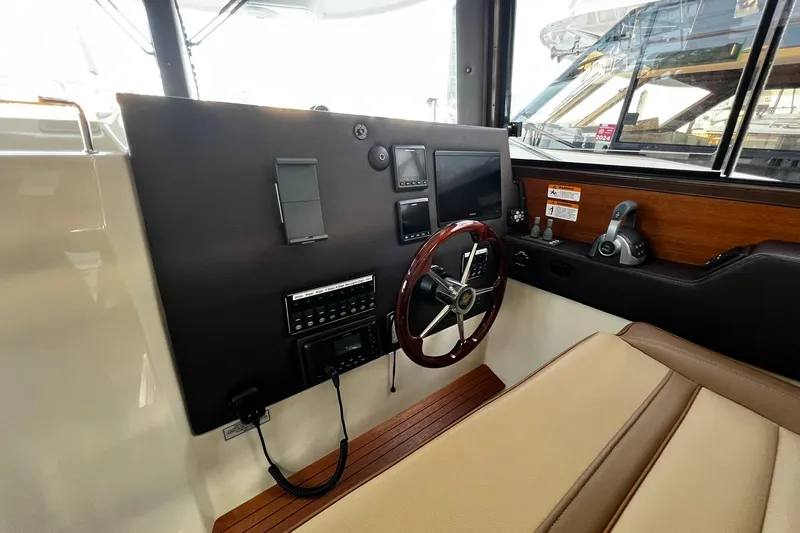 Slide: The Image of 2021 Ranger Tugs R-29S helm with steering wheel, control panel, and navigation equipment. - 12