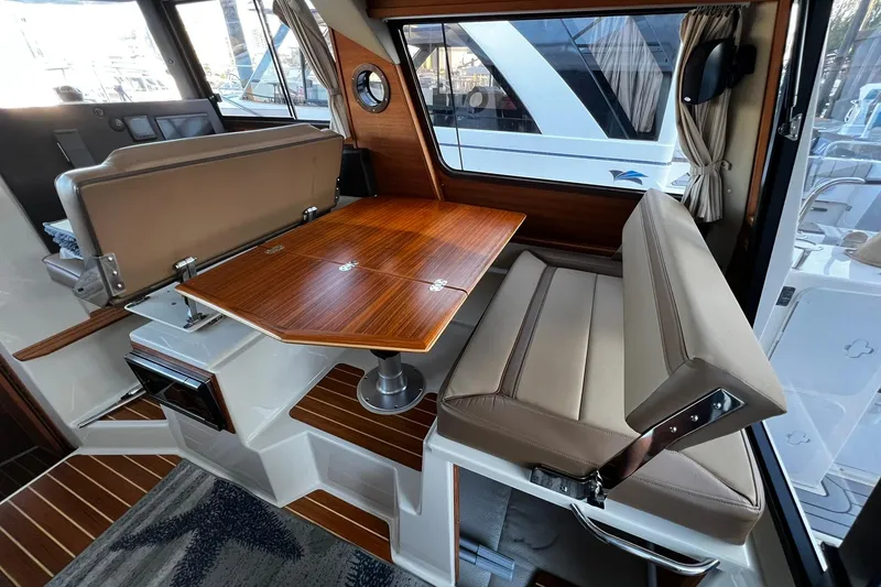 Slide: The Image of Interior of 2021 Ranger Tugs R-29S with wooden table and beige seating. - 8