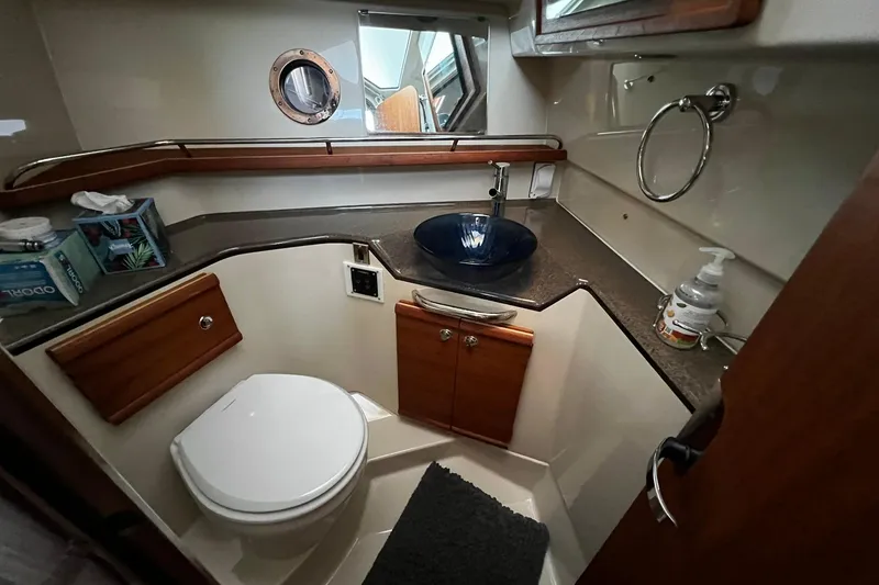 Slide: The Image of 2021 Ranger Tugs R-29S bathroom with modern sink, toilet, and wooden cabinetry. - 9
