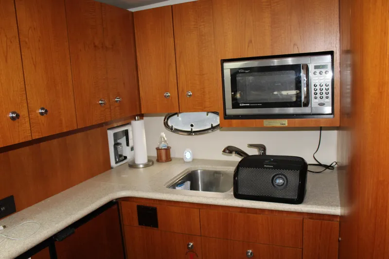 Slide: The Image of 2002 Tiara Yachts 3800 Open kitchen with microwave, sink, and wooden cabinets. - 46