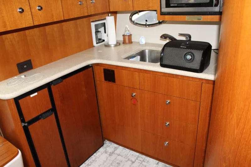 Slide: The Image of 2002 Tiara Yachts 3800 Open kitchen with wooden cabinets and countertop. - 47